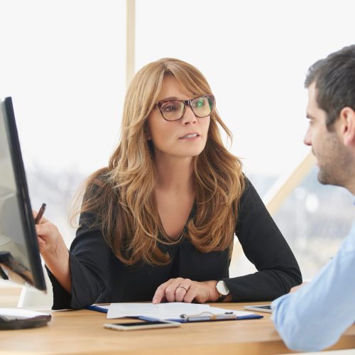 Executive,Middle,Aged,Businesswoman,Sitting,At,Desk,In,Front,Of